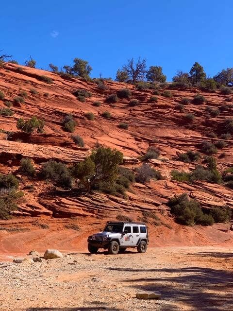 Jeep beneath sandstone cliffs