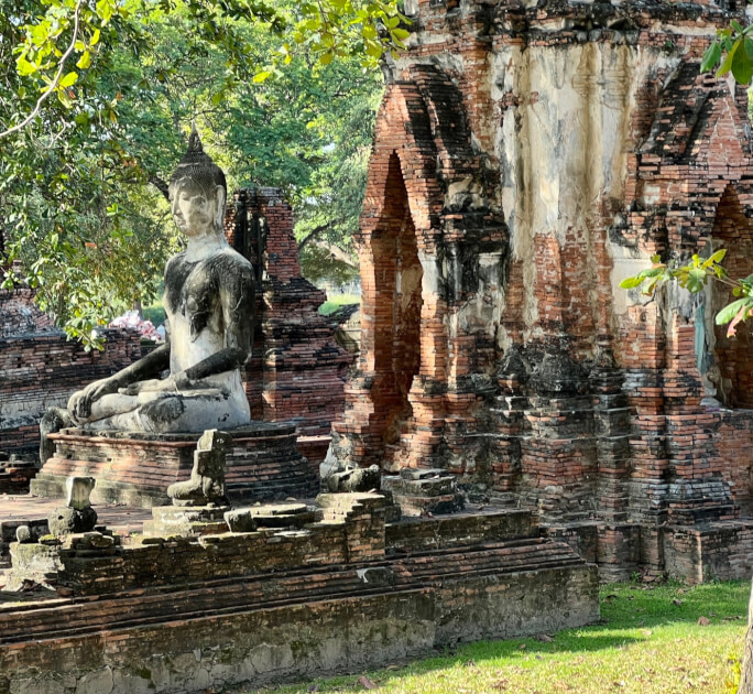 stone Buddha and other crumbling ruins of ancient Ayutthaya Thailand